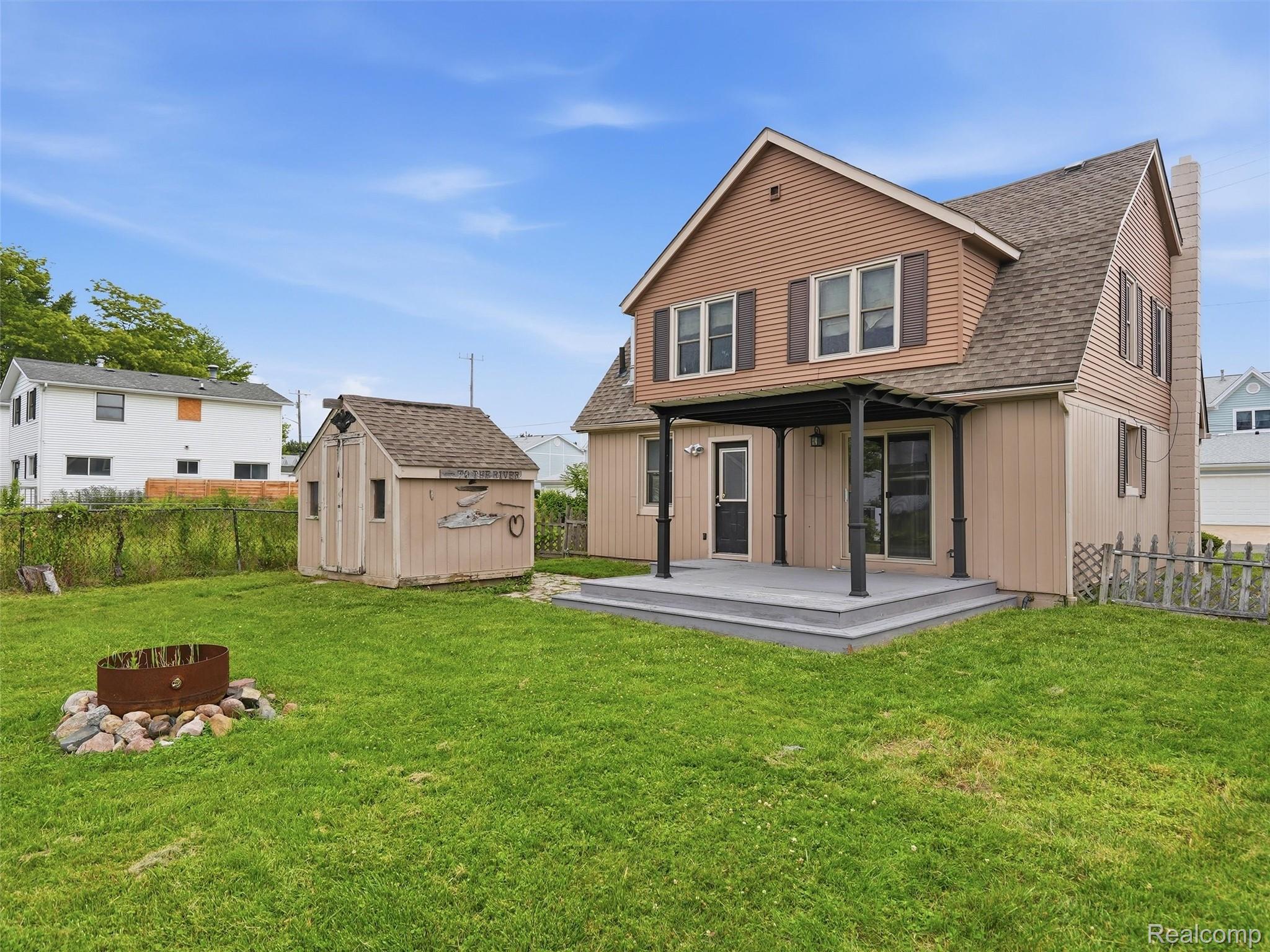 117 Kenyon Road Algonac, MI 48001 - Photo 38 of 47 Expansive backyard featuring a shaded patio, a detached storage shed, and a stone-lined fire pit area