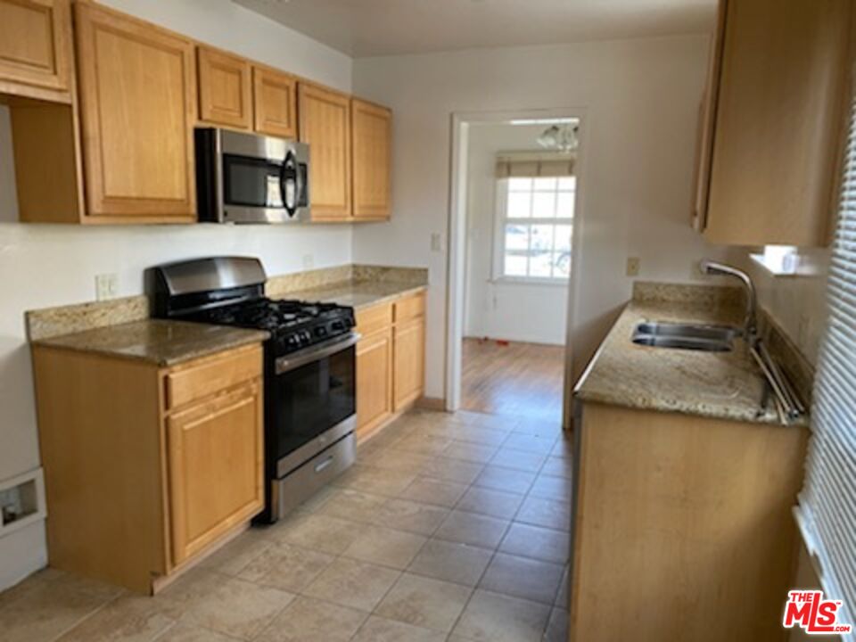 17600 Calvert Street Encino, CA 91316 - Photo 18 of 21 a kitchen with granite countertop a sink a stove top oven and cabinetry