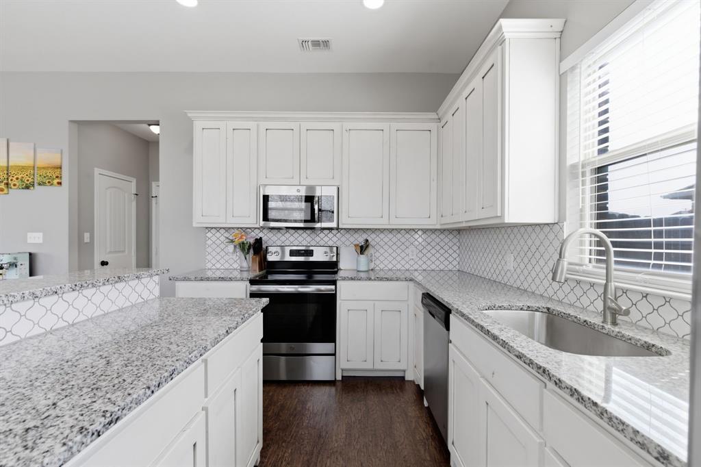 711 Hadley Lane Valley View, TX 76272 - Photo 11 of 40 Kitchen with stainless steel appliances, light stone countertops, white cabinets, dark wood-type flooring, and recessed lighting