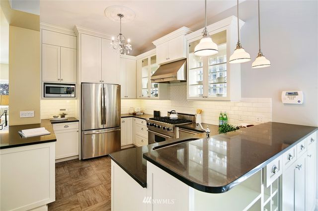 a kitchen with stainless steel appliances granite countertop a sink a stove and a refrigerator