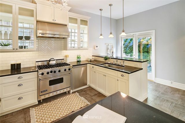 a kitchen with granite countertop a stove a sink and a refrigerator