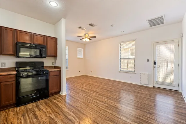 a view of a kitchen with a stove wooden cabinet wooden floor and chandelier