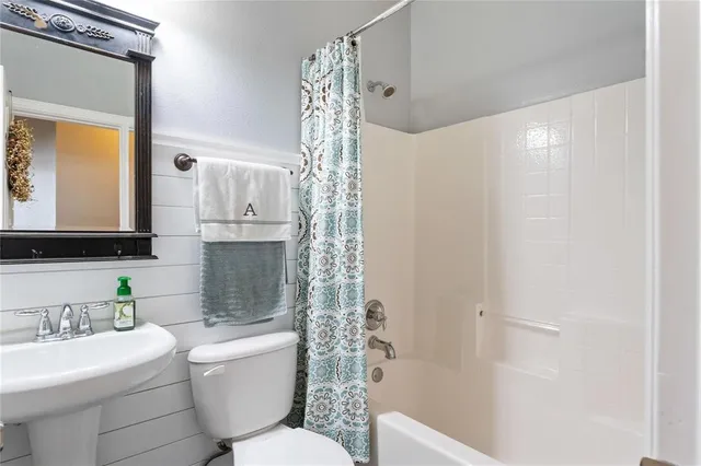 a bathroom with a toilet a sink a tub and mirror