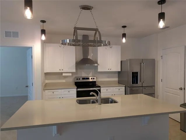 a kitchen with kitchen island a counter top space a sink stainless steel appliances and cabinets