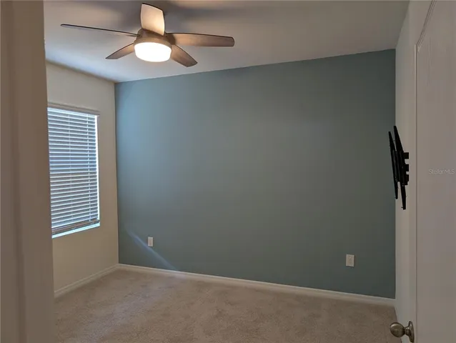 an empty room with windows and fan