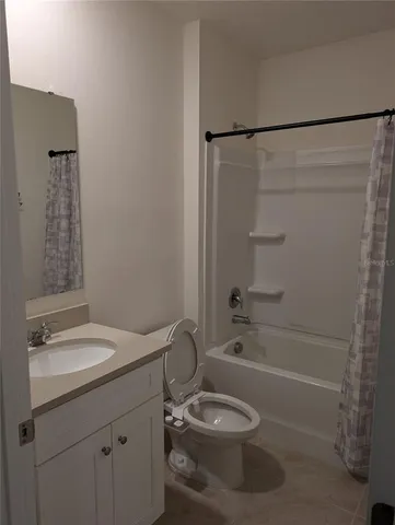 a bathroom with a granite countertop bathtub shower sink vanity and toilet