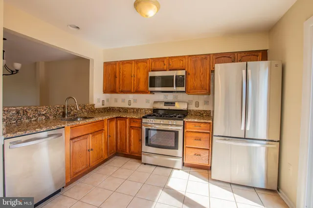 a kitchen with stainless steel appliances granite countertop a refrigerator sink and stove