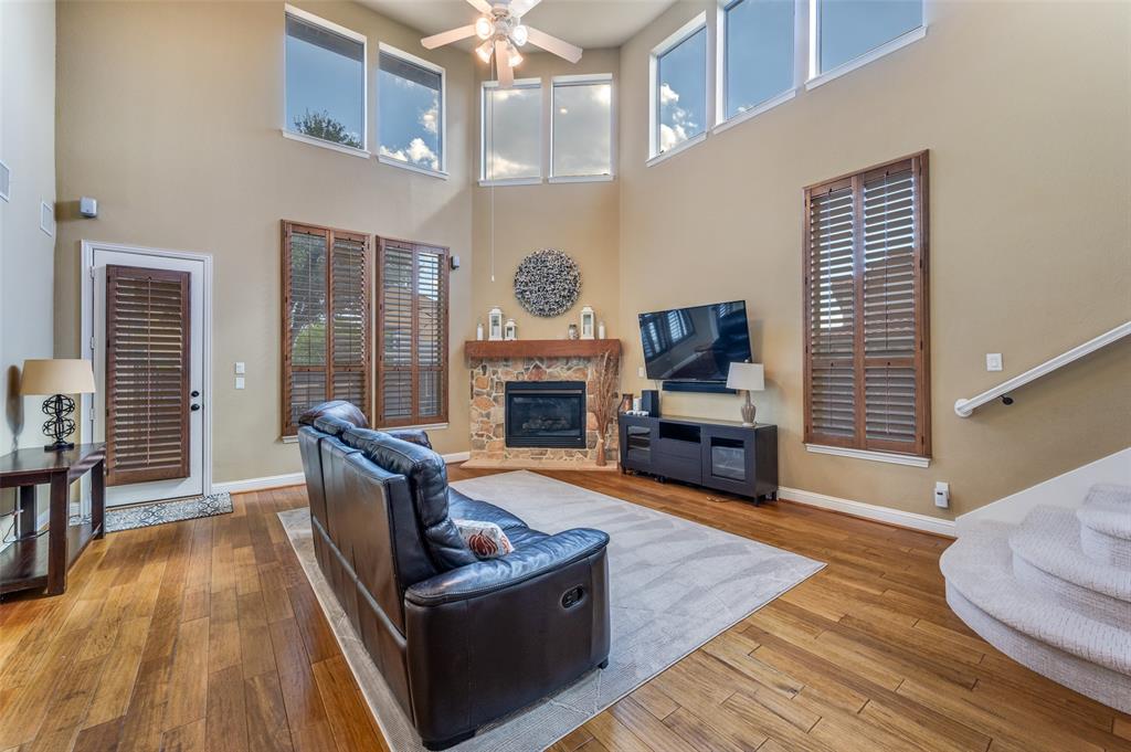 810 Redondo Irving, TX 75039 - Photo 11 of 24 Living room featuring a fireplace, hardwood / wood-style floors, a high ceiling, ceiling fan, and healthy amount of natural light