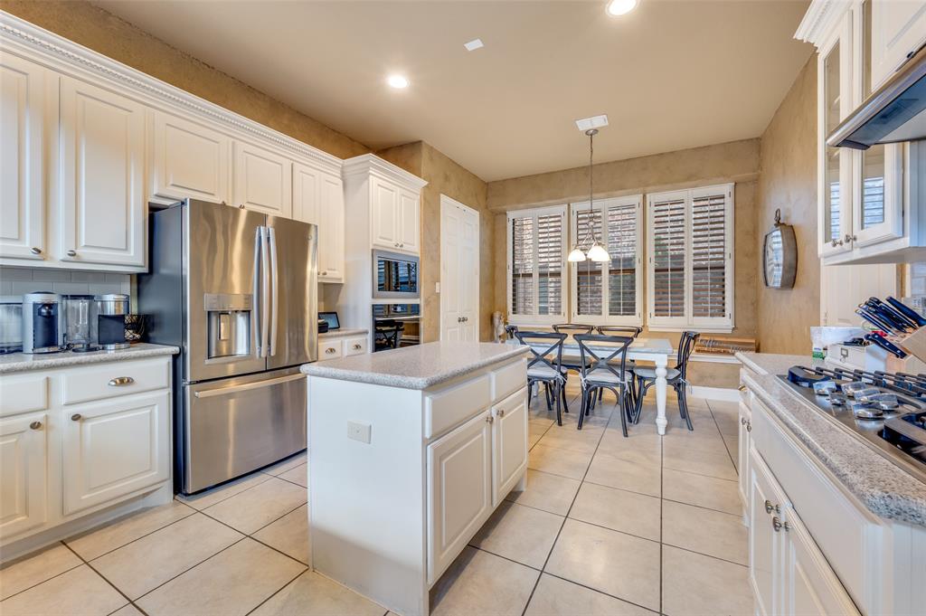 810 Redondo Irving, TX 75039 - Photo 12 of 24 Kitchen featuring white cabinetry, stainless steel appliances, decorative light fixtures, light tile patterned floors, and a kitchen island