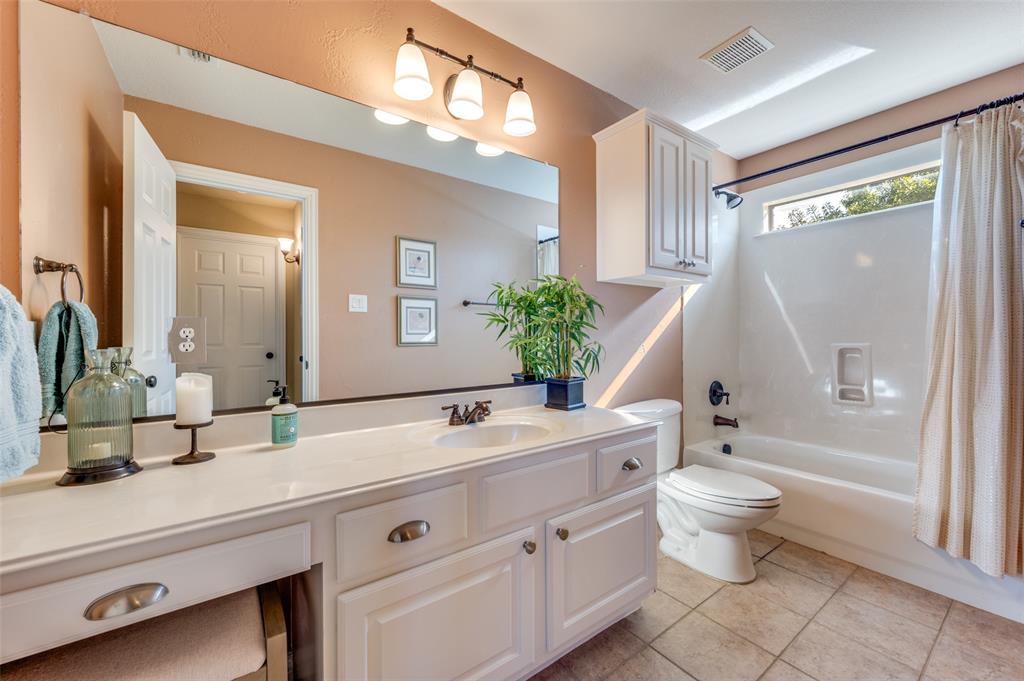 810 Redondo Irving, TX 75039 - Photo 22 of 24 Full bathroom in hallway upstairs featuring shower / bath combo with shower curtain, light tile patterned floors, and vanity