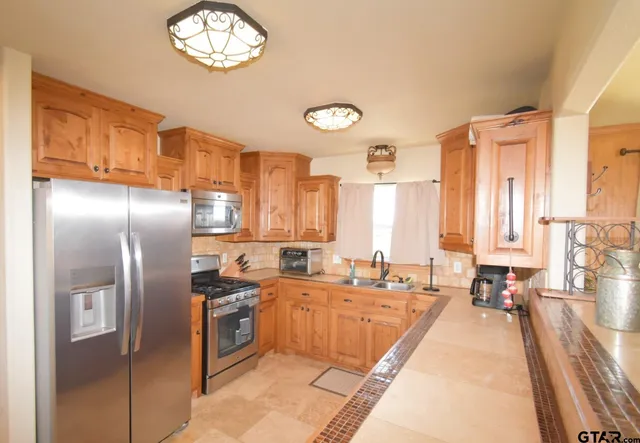 a large kitchen with stainless steel appliances a sink a stove and a refrigerator