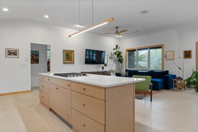 a large white room with kitchen island stainless steel appliances sink and cabinets