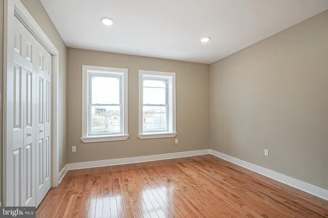an empty room with wooden floor and windows
