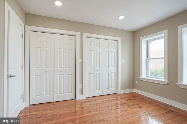 an empty room with wooden floor closet and windows