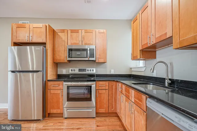 a kitchen with stainless steel appliances granite countertop a refrigerator a stove a sink and a microwave