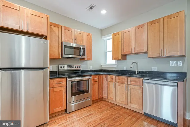 a kitchen with granite countertop a refrigerator stove top oven and sink