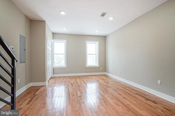 a view of empty room with wooden floor and fan