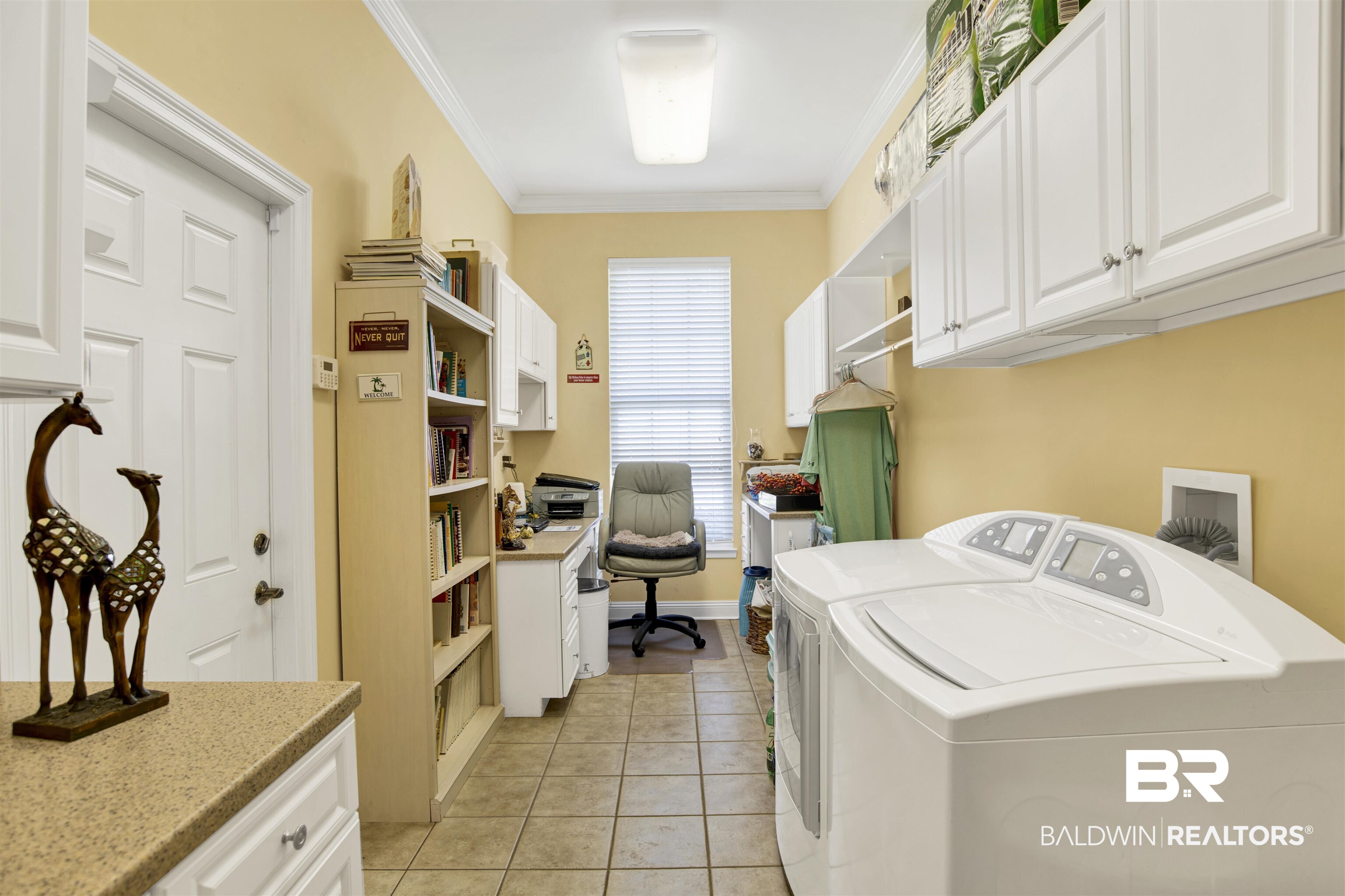 23014 Carnoustie Drive Foley, AL 36535 - Photo 25 of 49 Laundry area featuring washer and dryer, crown molding, cabinet space, light tile patterned flooring, and a desk