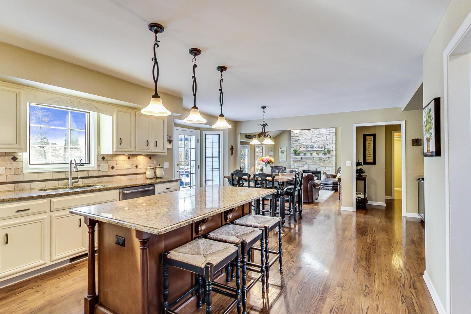 2616 High Meadow Road Naperville, IL 60564 - Photo 4 of 47 a kitchen with stainless steel appliances granite countertop a stove a refrigerator a kitchen island a dining table and chairs with wooden floor