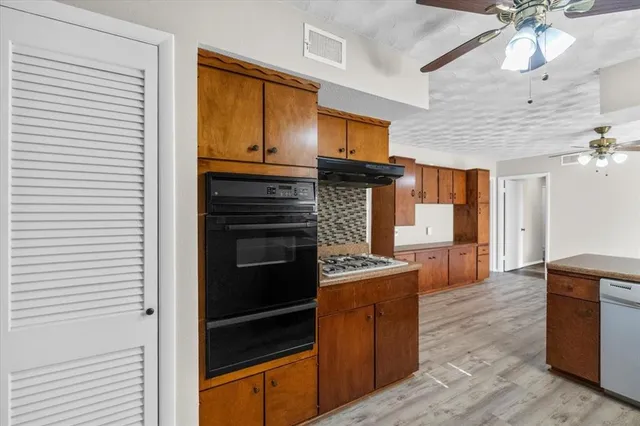 a kitchen with stainless steel appliances kitchen island granite countertop a stove and cabinets
