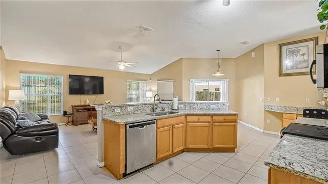 a open kitchen with stainless steel appliances granite countertop a stove top oven a sink dishwasher and white cabinets with wooden floor