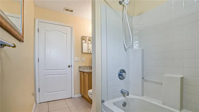 a bathroom with a granite countertop bathtub shower and toilet