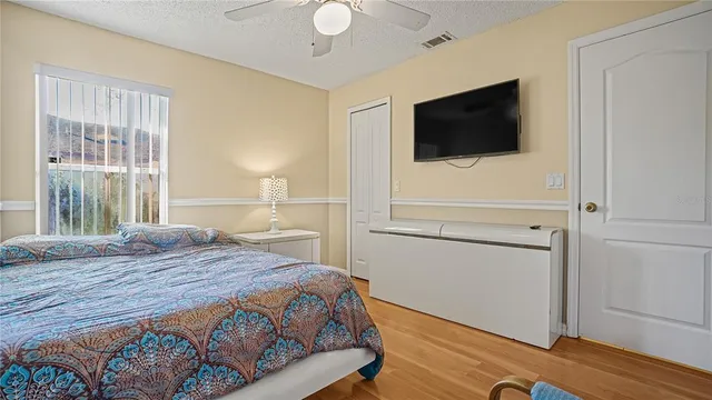 a bedroom with a bed tv and wooden floor