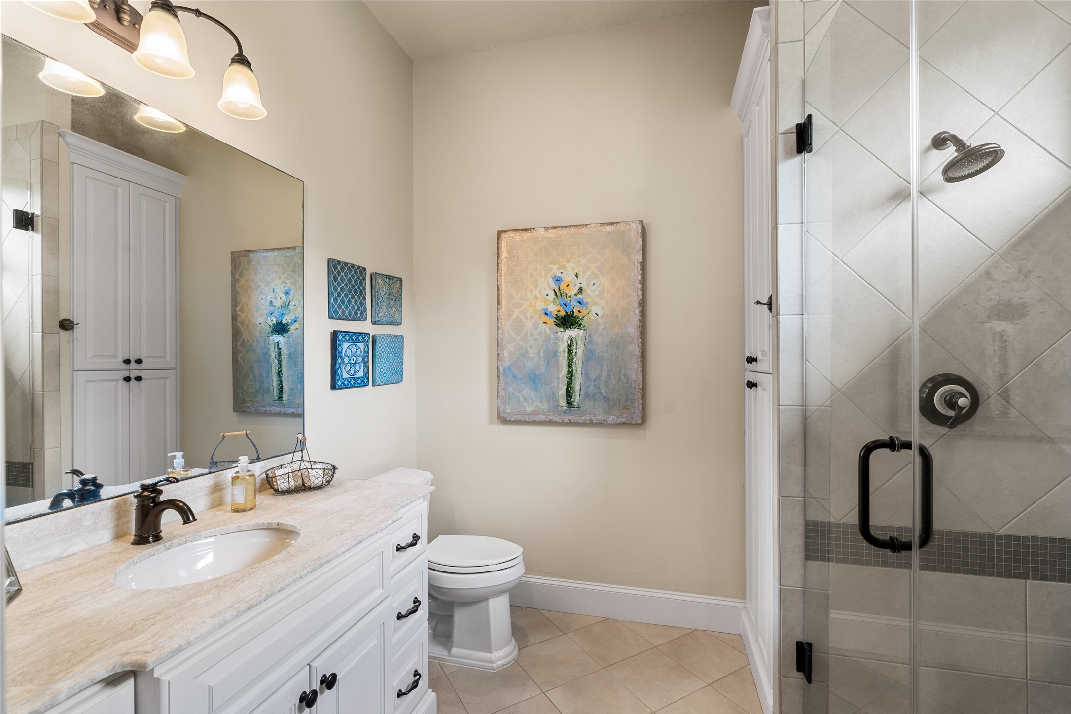 12349 Longmire Trace Conroe, TX 77304 - Photo 30 of 48 Bright bathroom featuring a long double-sink vanity, oversized mirror, and glass-enclosed tiled shower.
