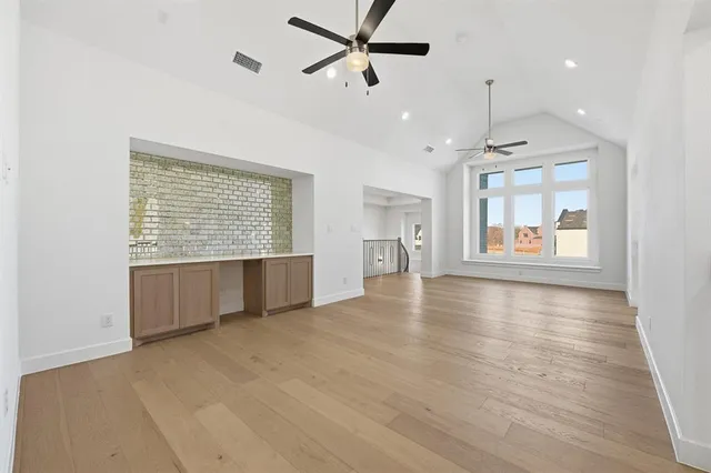 an empty room with wooden floor ceiling fan and windows
