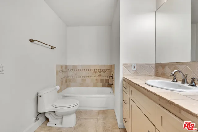 a bathroom with a granite countertop bathtub sink vanity mirror and toilet