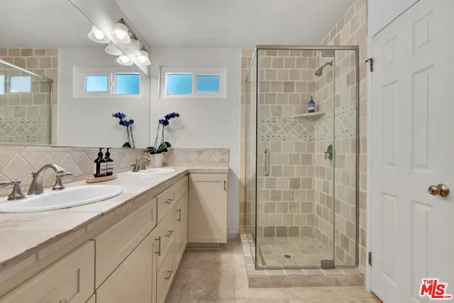 a bathroom with a double vanity sink mirror and shower