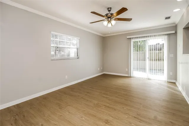 a view of an empty room with a window and wooden floor