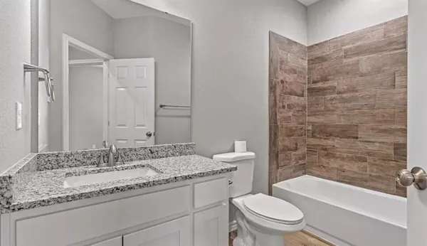 a bathroom with a granite countertop toilet a sink and bathtub