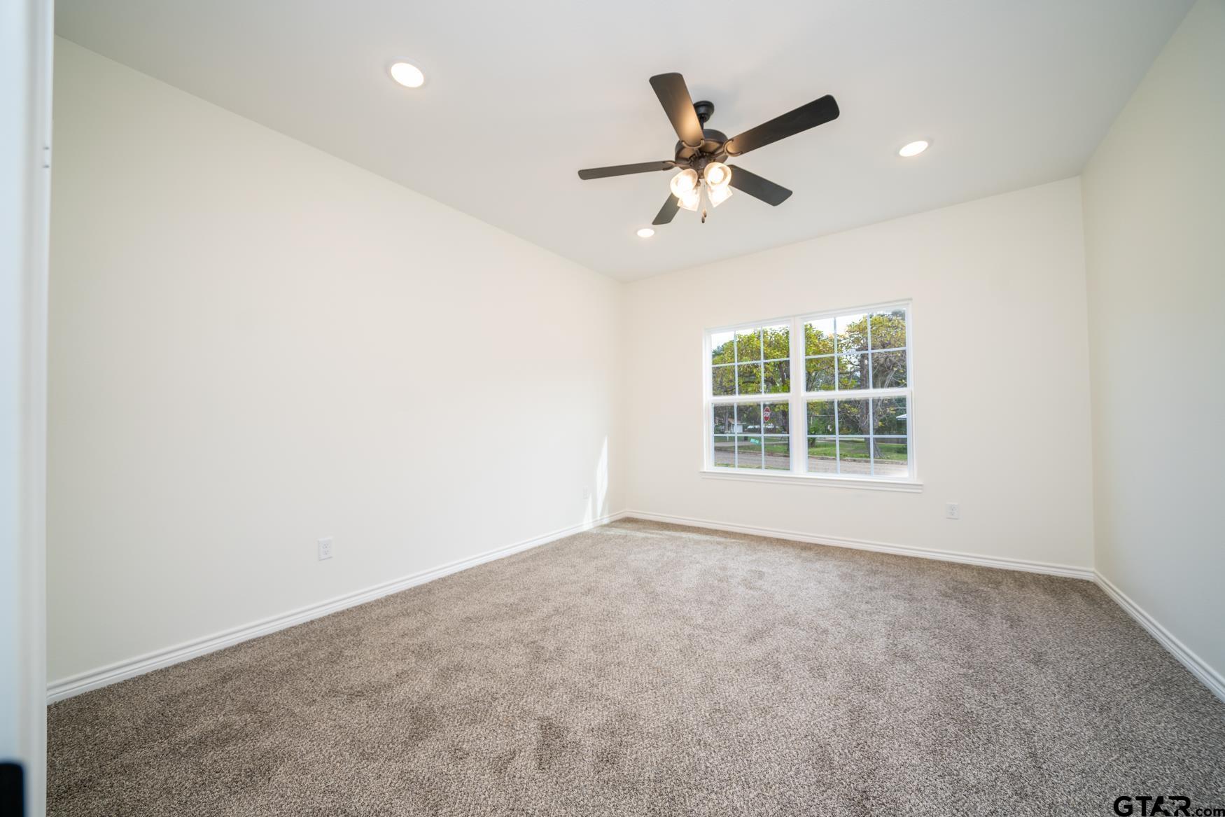 309 Stevens Street Gilmer, TX 75645 - Photo 12 of 28 an empty room with a window and a fan