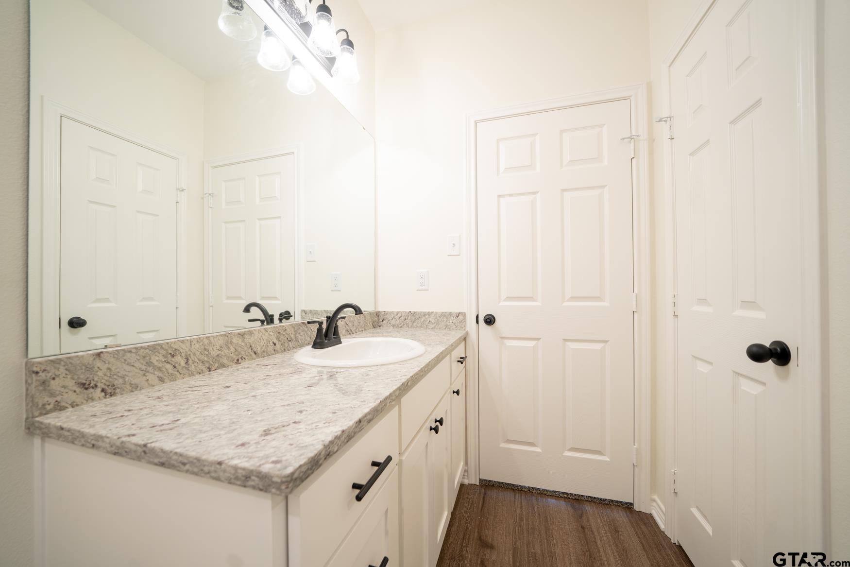 309 Stevens Street Gilmer, TX 75645 - Photo 18 of 28 a bathroom with a granite countertop sink and a mirror