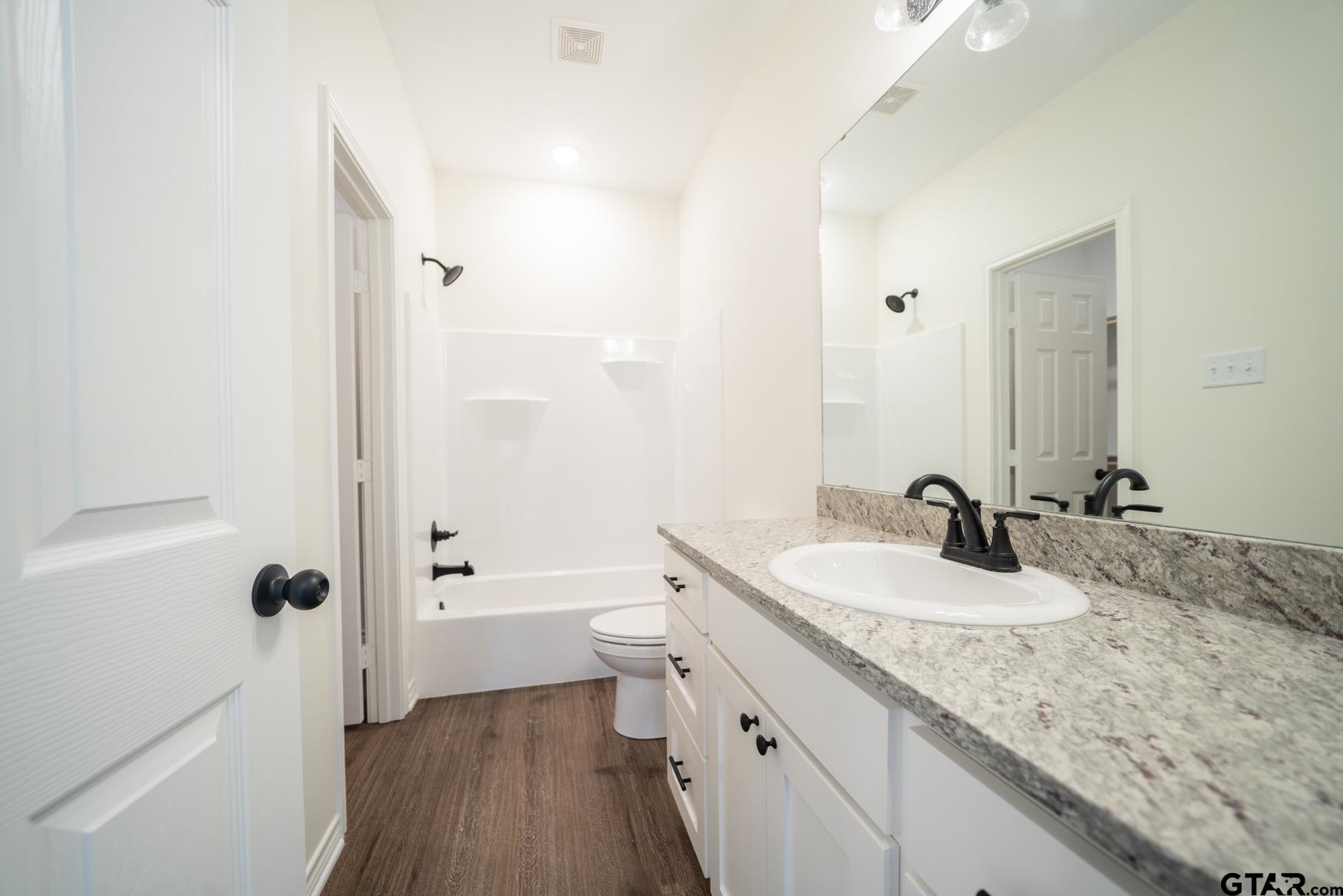 309 Stevens Street Gilmer, TX 75645 - Photo 20 of 28 a bathroom with a granite countertop sink a toilet and shower