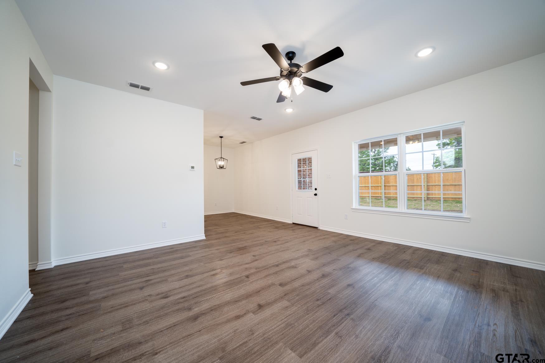 309 Stevens Street Gilmer, TX 75645 - Photo 2 of 28 a view of an empty room with wooden floor and a window
