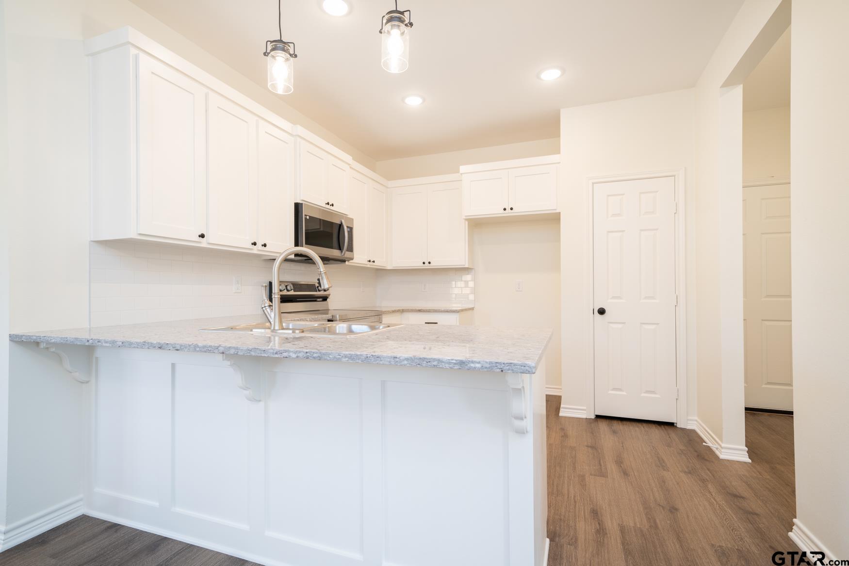 309 Stevens Street Gilmer, TX 75645 - Photo 9 of 28 a kitchen with kitchen island white cabinets and stainless steel appliances