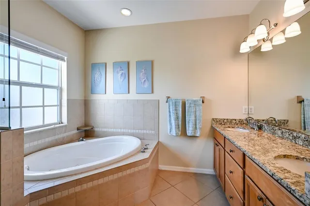 a spacious bathroom with a granite countertop tub a sink and a large mirror