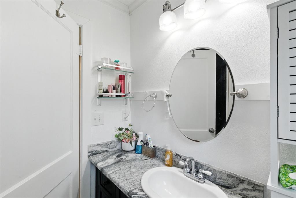 116 West 7th Street Weatherford, TX 76086 - Photo 17 of 26 a bathroom with a granite countertop sink a mirror and vanity