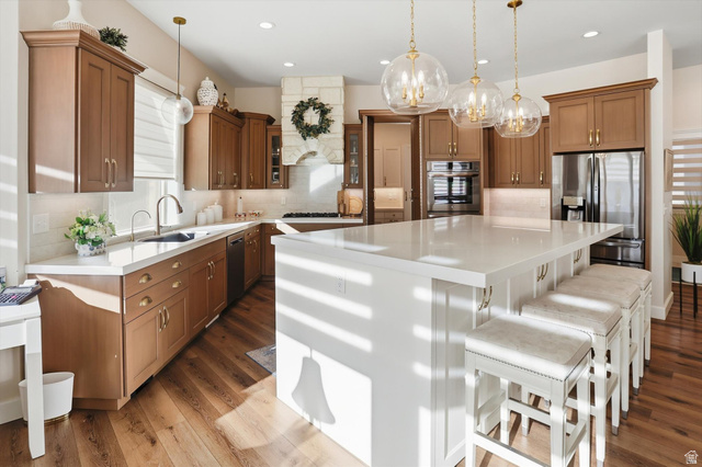534 East Fish Hatchery Road Mantua, UT 84324 - Photo 22 of 87 Two tone kitchen with dual tone cabinetry, a large island, stainless steel appliances, backsplash, and a breakfast bar