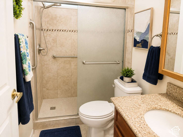 1526 North Dixie Downs Road, Unit 29 St. George, UT 84770 - Photo 12 of 16 Walk-in shower with tiled surround and integrated grab bars, complemented by a wood-finish vanity with a light-colored countertop
