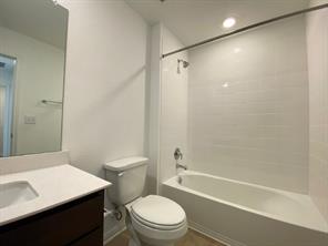 213 Saide Street Georgetown, TX 78626 - Photo 26 of 32 Bathroom featuring a white subway tile shower surround, a built-in bathtub with chrome fixtures, a dark wood-finish vanity with a white countertop and integrated sink, and recessed lighting