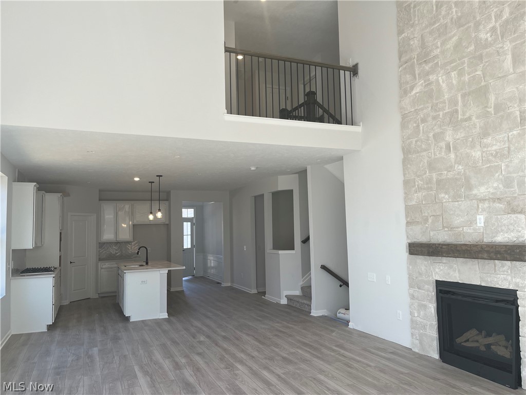745 River Run Road Aurora, OH 44202 - Photo 7 of 7 Open Floor Plan with view of kitchen and gathering room featuring a stone fireplace, a towering ceiling, and wood-style floors