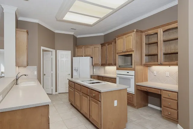 a kitchen that has a lot of white cabinets and stainless steel appliances
