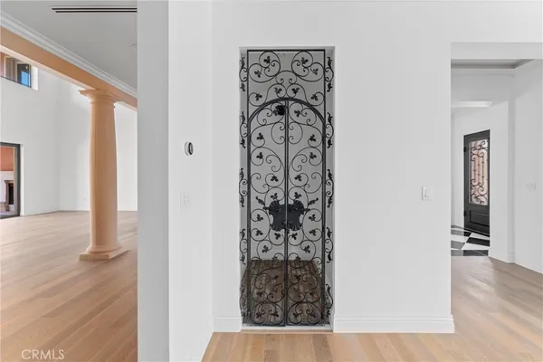 an empty room with wooden floor chandelier and windows