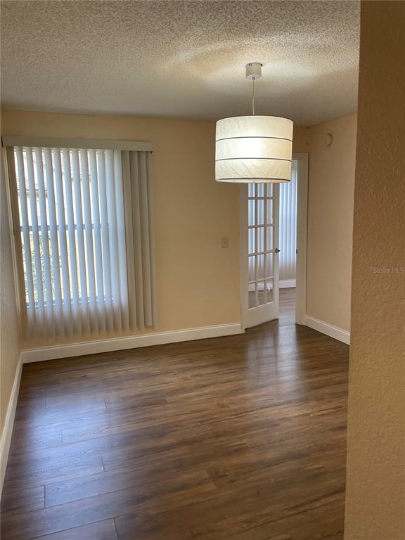 5144 Conroy Road, Unit 32 Orlando, FL 32811 - Photo 12 of 16 an empty room with wooden floor chandelier and windows