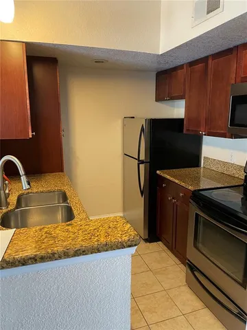 a kitchen with granite countertop a sink stove and refrigerator