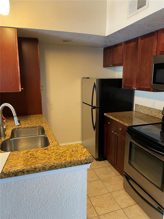 5144 Conroy Road, Unit 32 Orlando, FL 32811 - Photo 2 of 16 a kitchen with granite countertop a sink stove and refrigerator