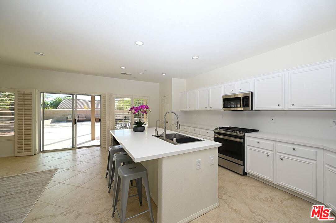 699 Alta Ridge Palm Springs, CA 92262 - Photo 8 of 31 a kitchen with stainless steel appliances granite countertop a sink and white cabinets